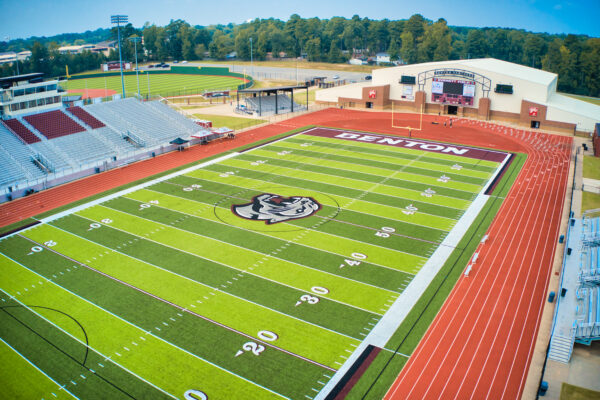 Aerial view of a high school stadium with a football field, running track, and perimeter fencing