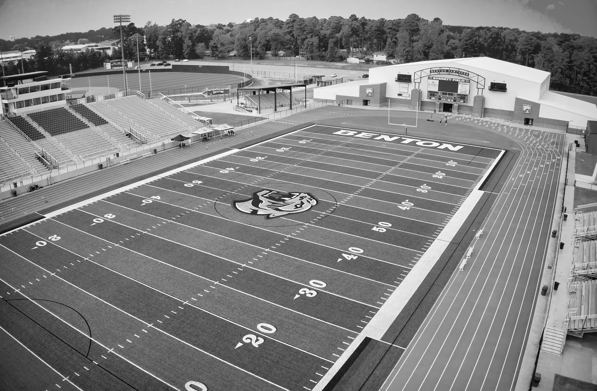 Aerial view of a high school stadium with a football field, running track, and perimeter fencing